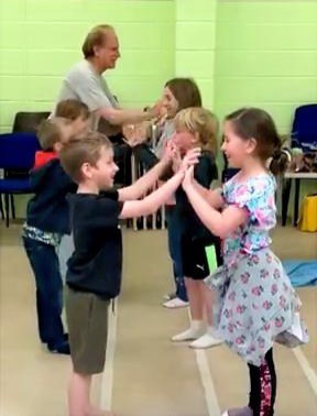 Young children singing and clapping together in a music class